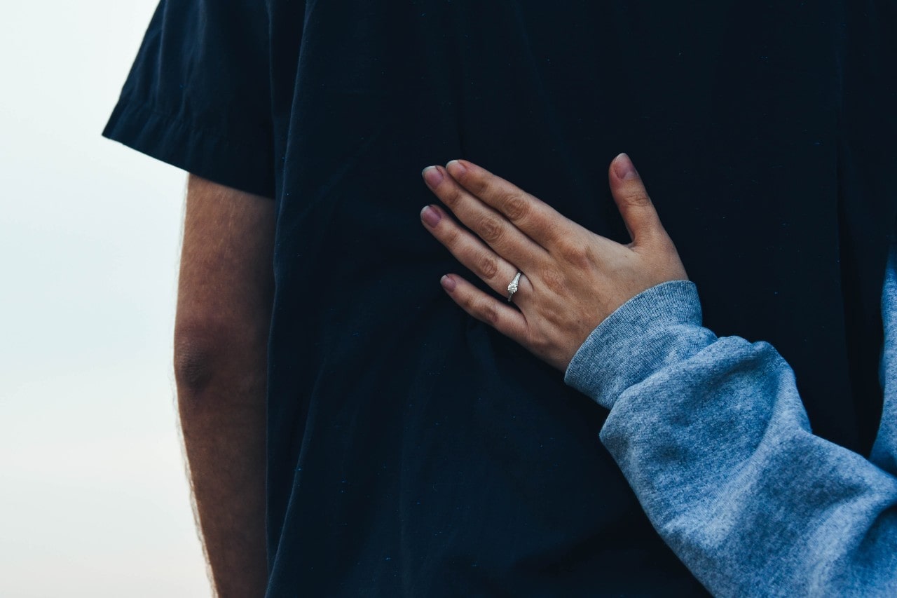 Woman proudly displays her glamorous engagement ring while encouraging someone via back pat