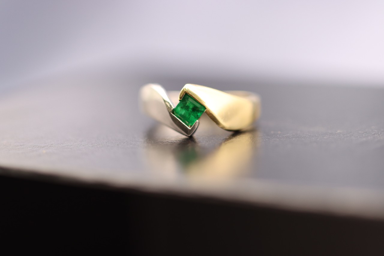 A solitaire princess cut emerald bezel set in a multi-metal band