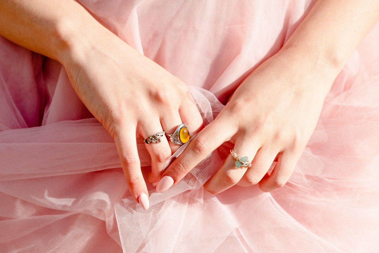 A woman in a pink tulle dress wearing multiple gemstone fashion rings