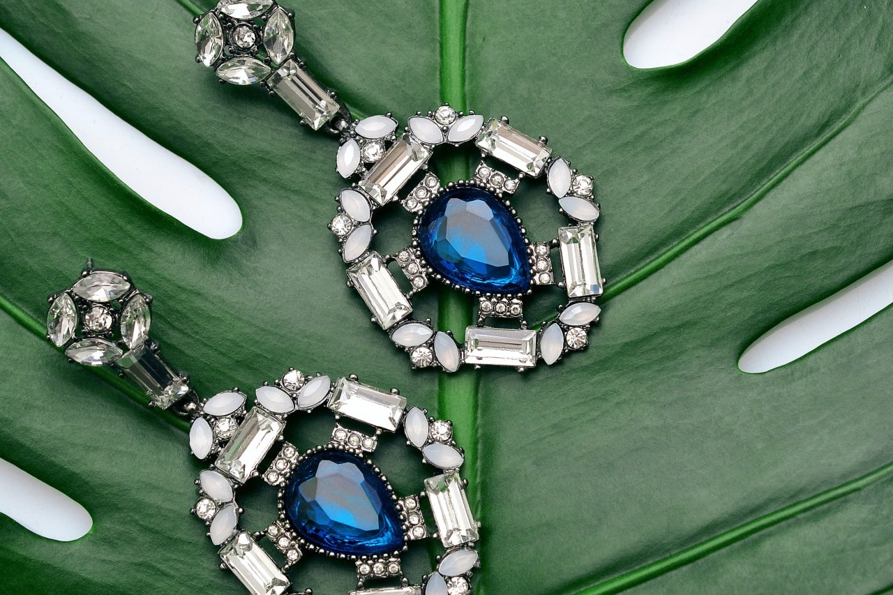 Sapphire and diamond earrings sitting on a leaf