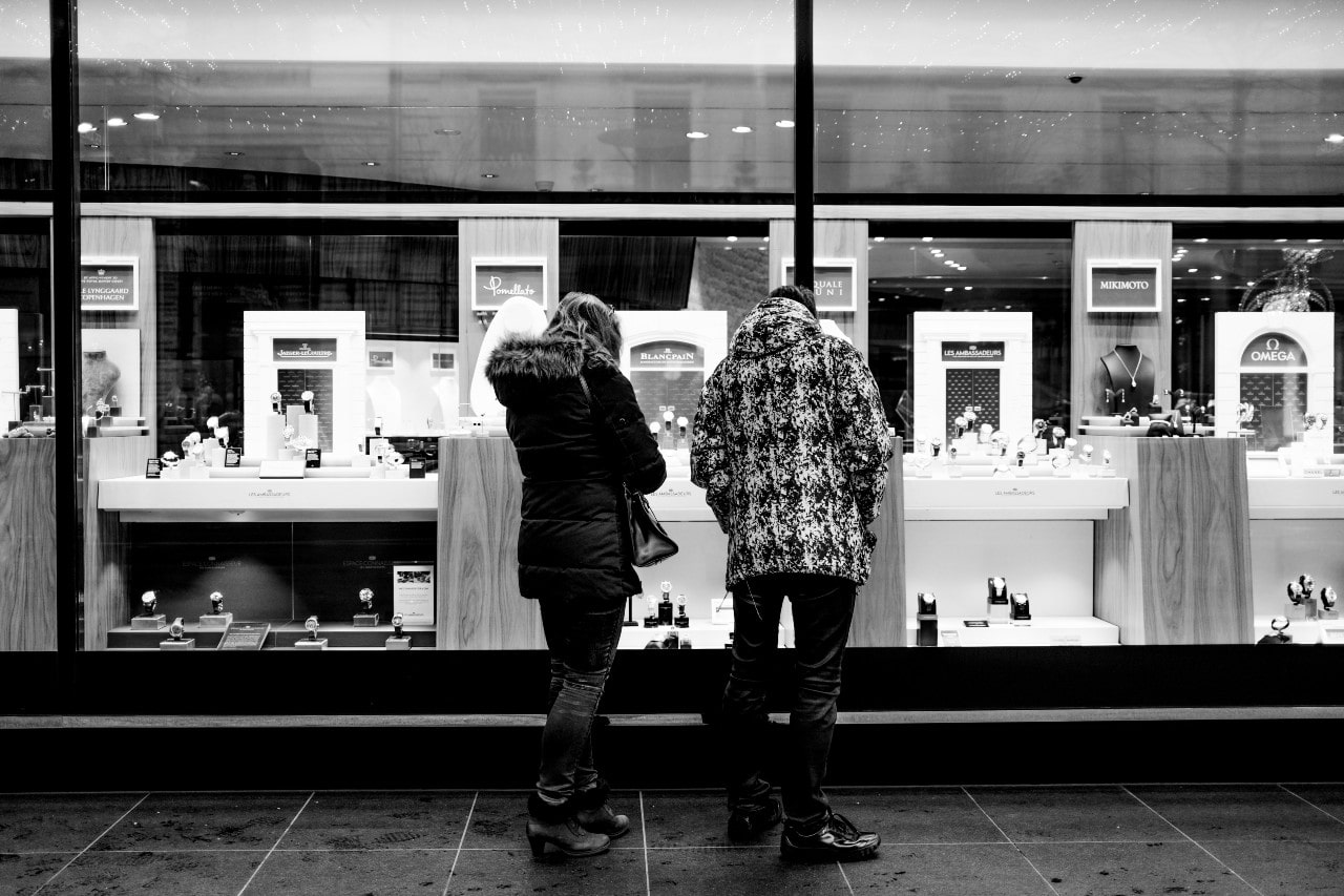 A couple looks through a jewelry store window at night