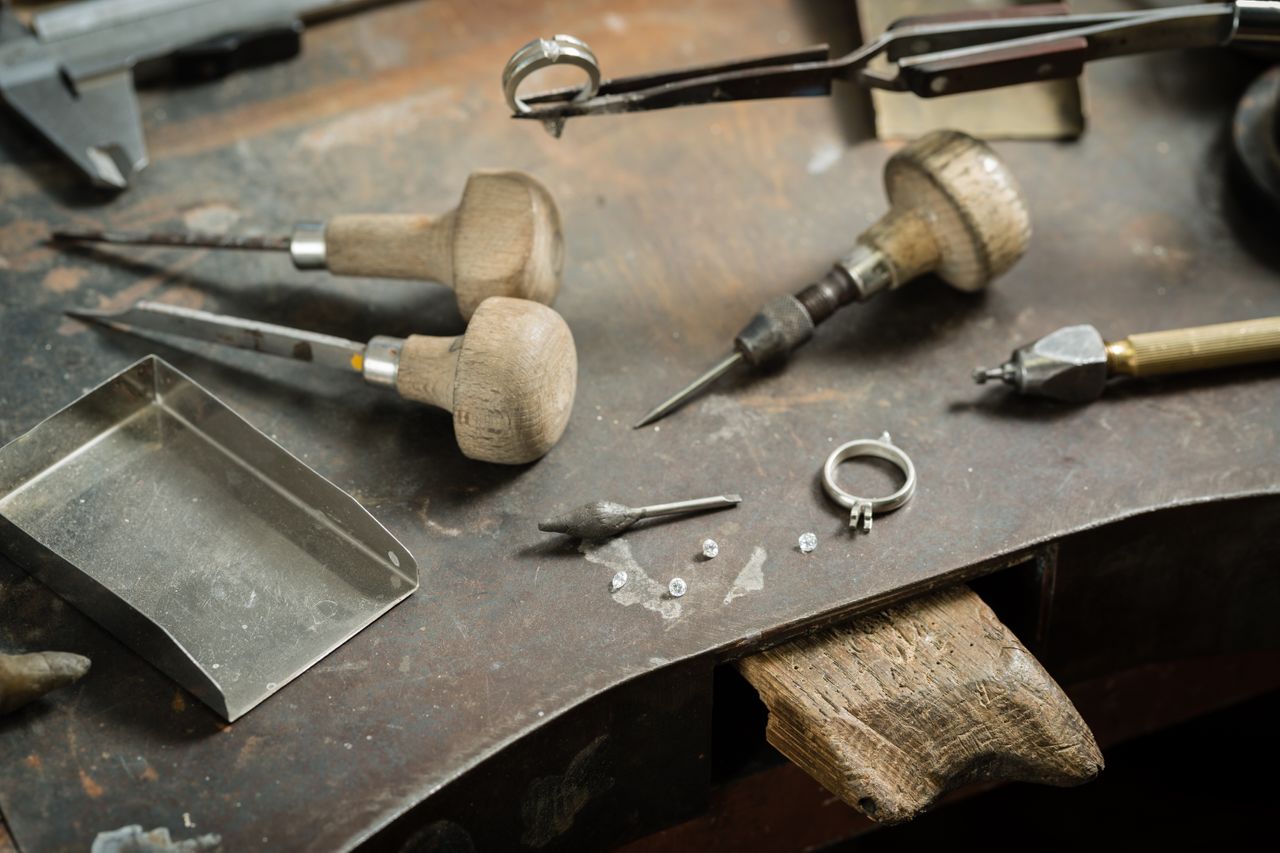 An abandoned jeweler’s workstation with tools, ring settings, and diamonds