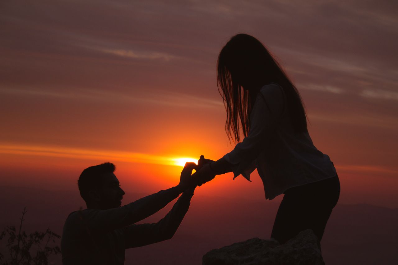A man proposes to his girlfriend at sunset