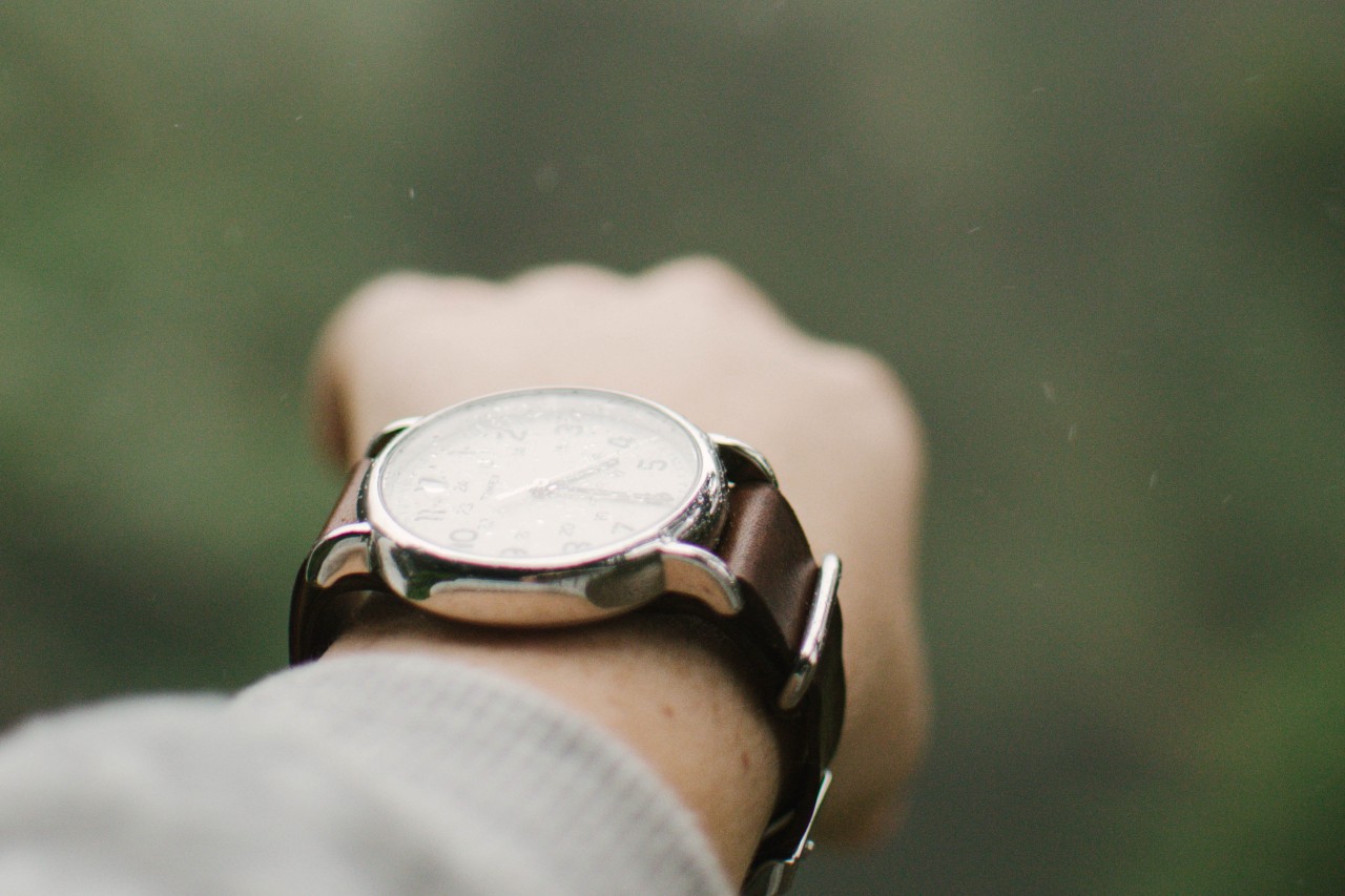 An outstretched arm wearing a silver and white watch with a brown leather strap