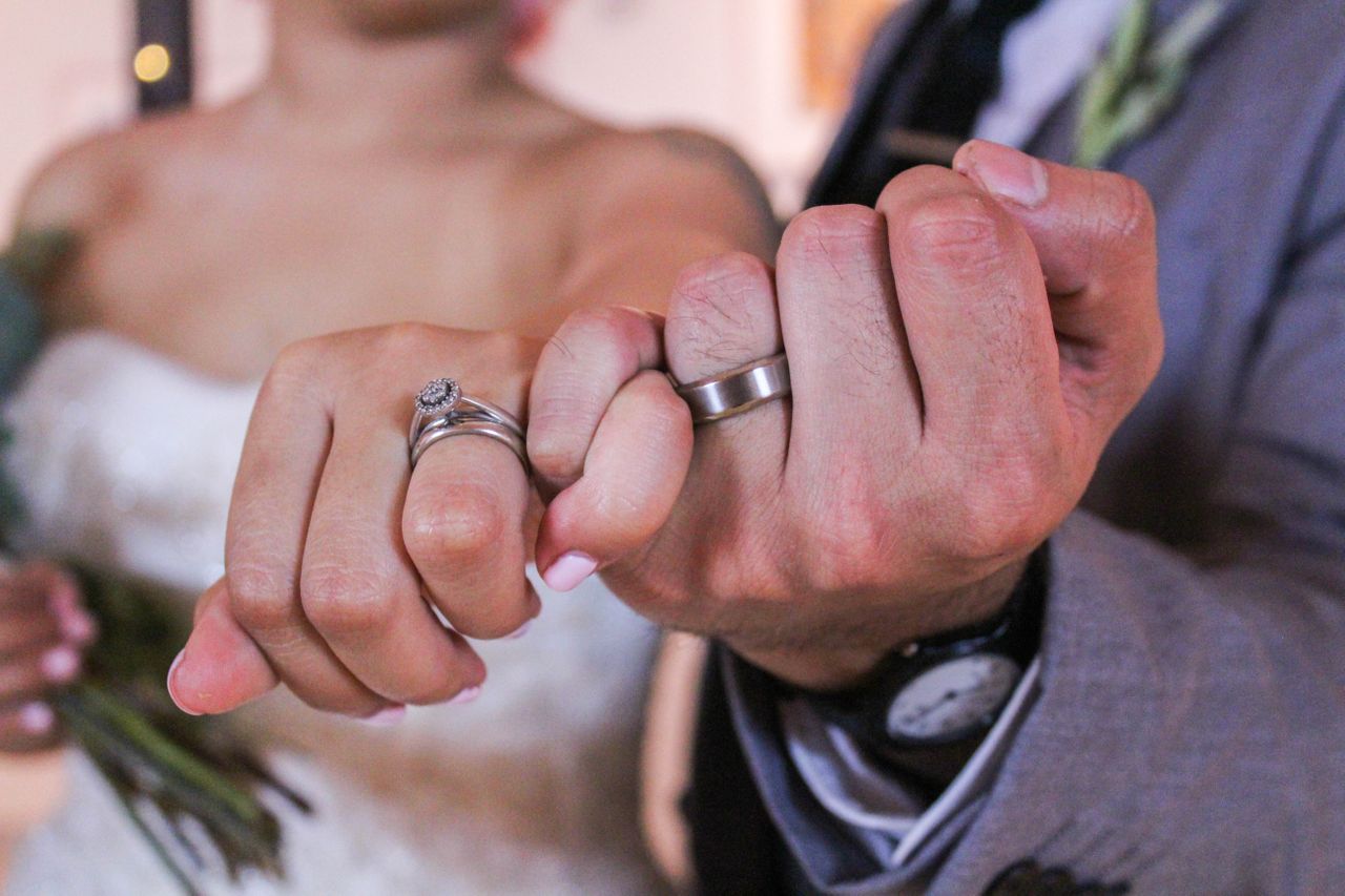 A newly married couple links pinkie fingers to show off their bridal jewelry