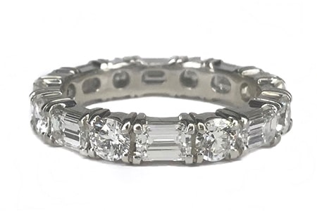 An eternity band features a combination of round-cut diamonds and emerald-cut diamonds