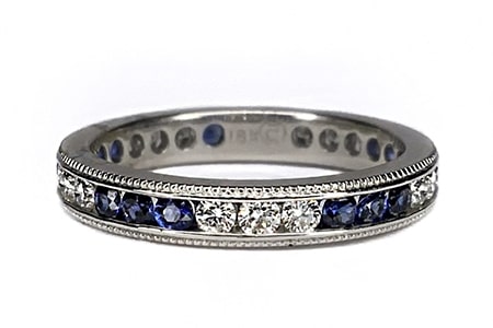 A sapphire birthstone anniversary band features a vintage-inspired channel setting