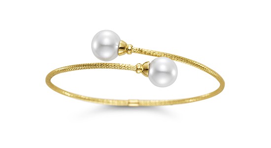 A yellow gold cuff bracelet adorned with two pearls