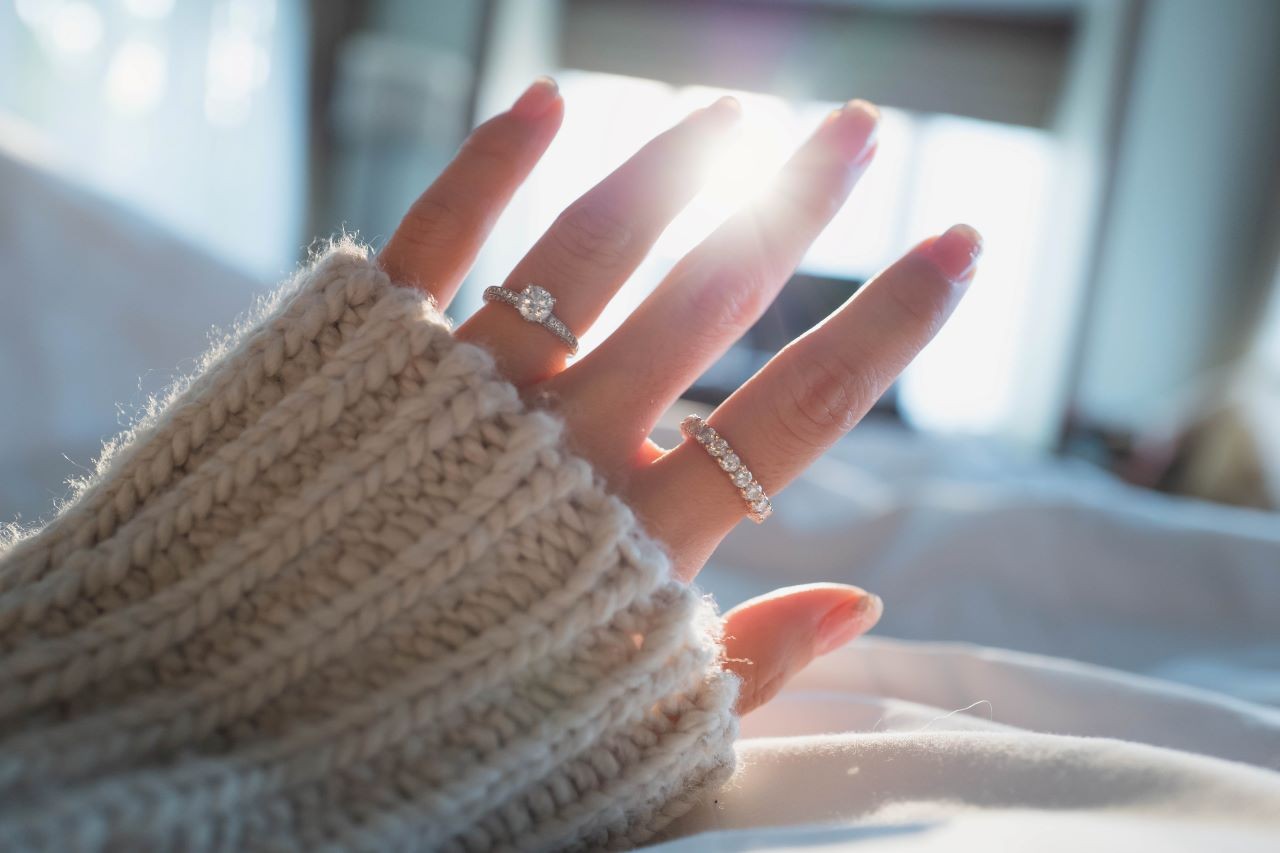 Woman wearing rings and holding her hand up to the sun