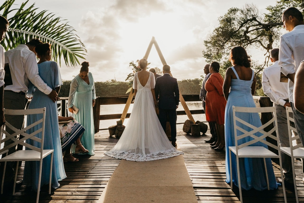 A bride and groom standing at the end of an alter outdoors