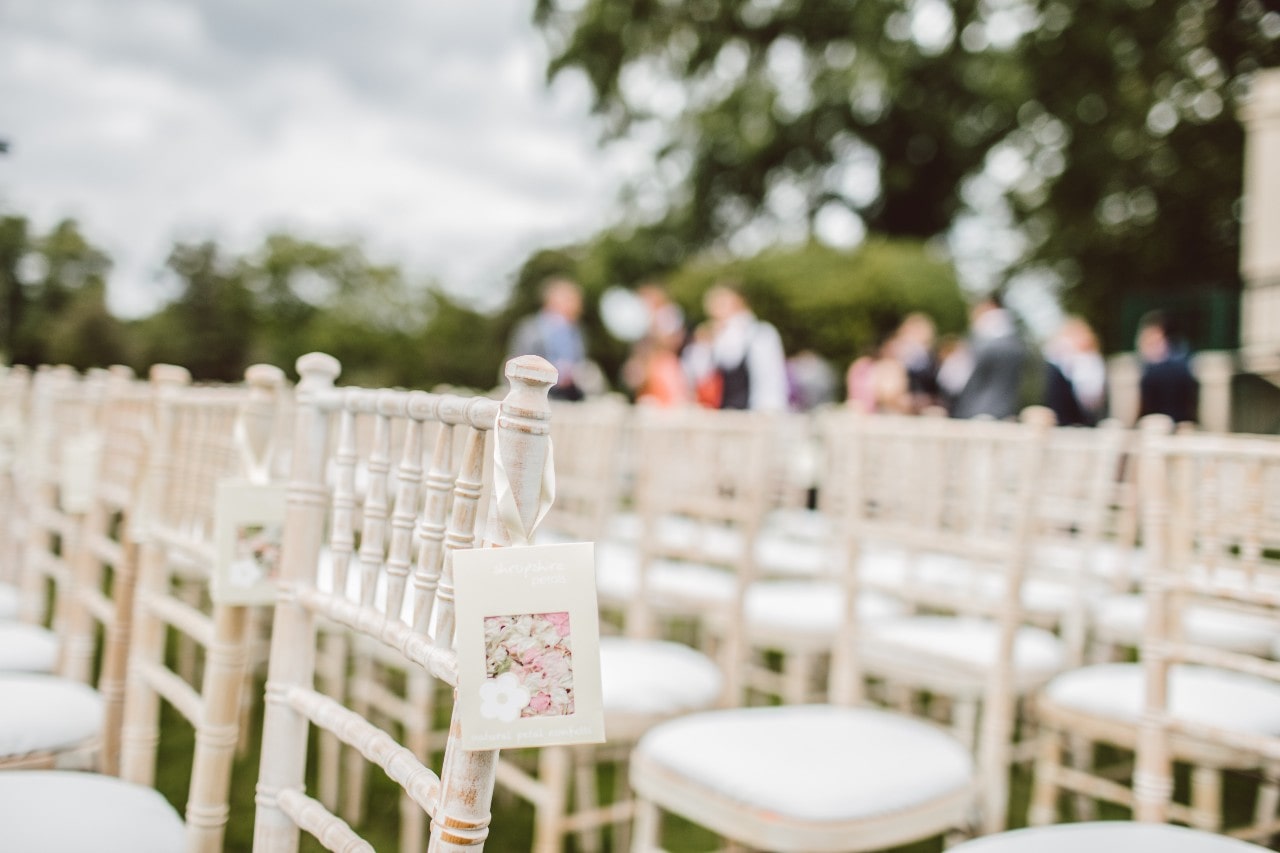Rows of white chairs set for an outdoor wedding ceremony