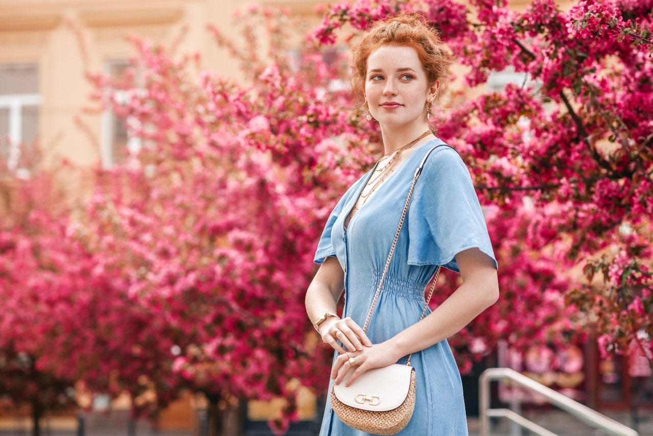 Woman wearing jewelry and a handbag with a floral background