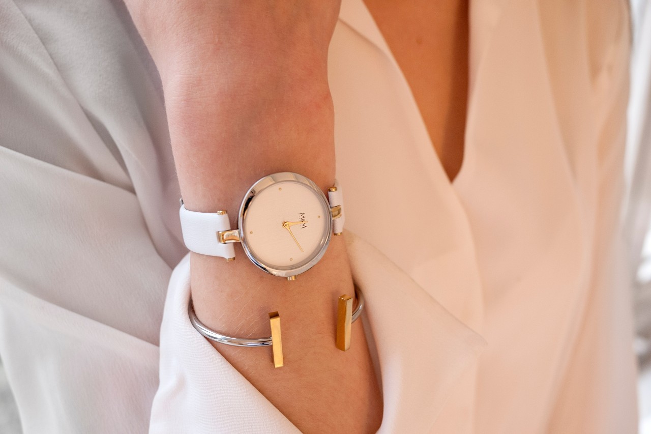 Close up image of a person wearing a white, silver and gold watch paired with a silver and gold bracelet