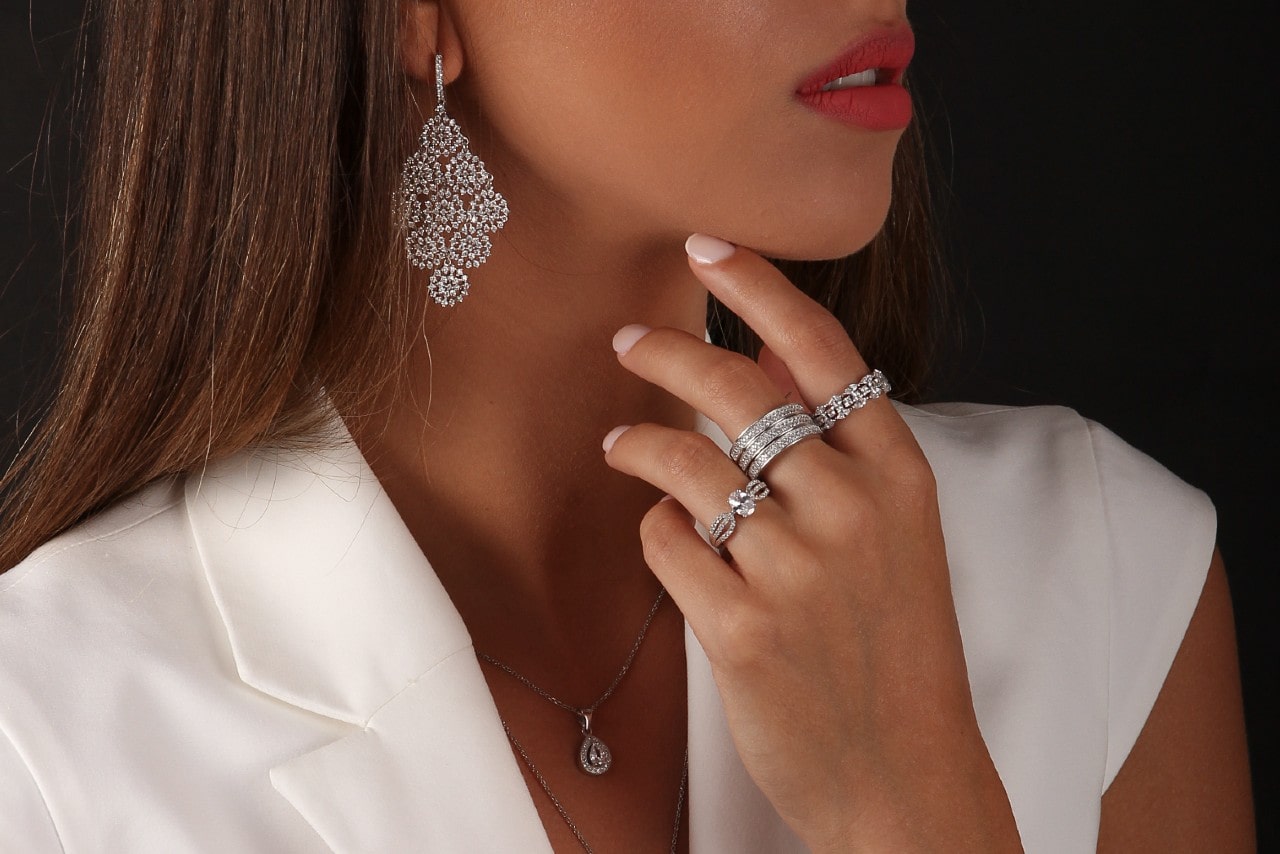 A woman in a white dress shirt wears diamond jewelry