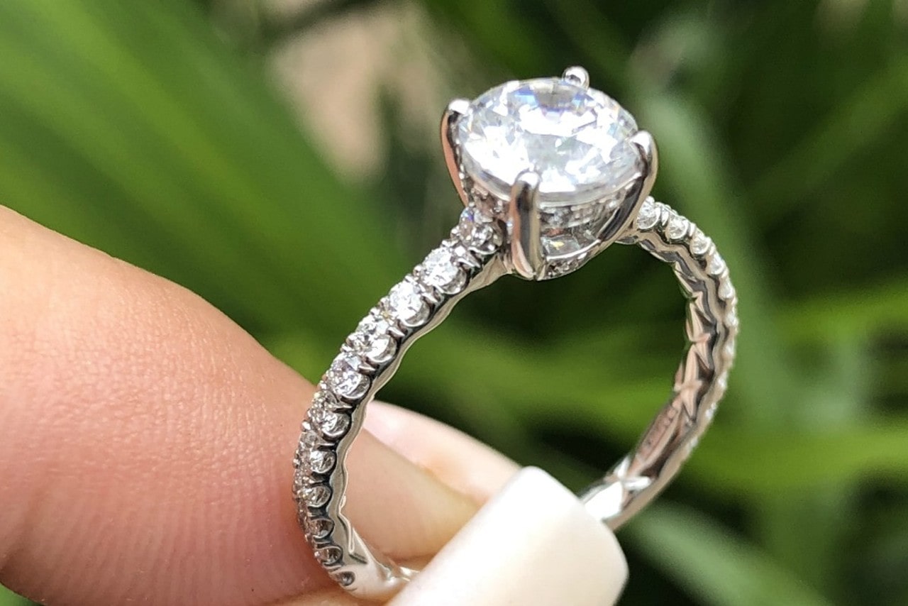 A woman holds a silver engagement ring in the sunlight.