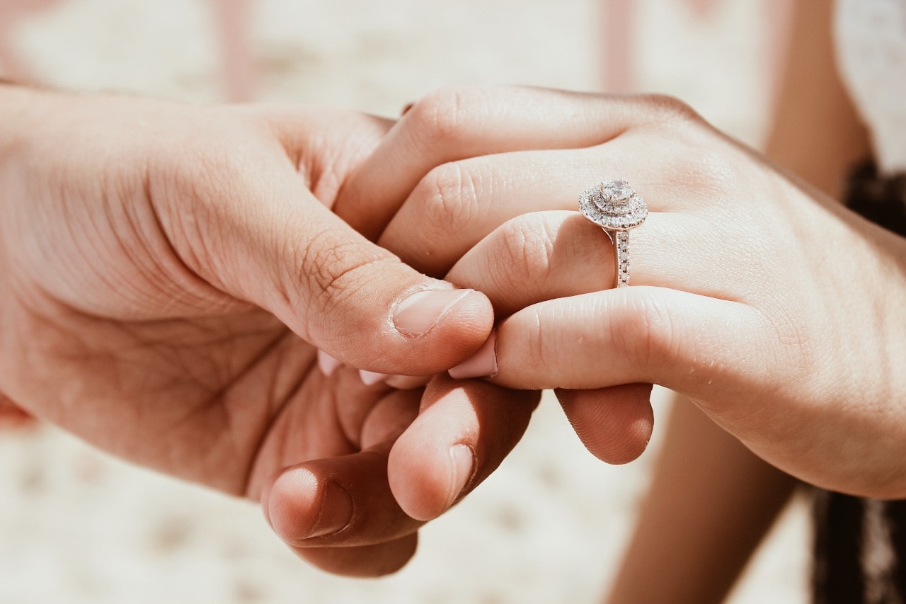 An engagement couple holds hands while in the sunlight.