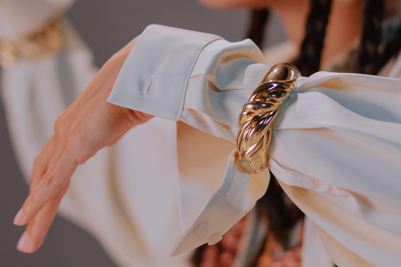 a woman’s wrist adorned with a chunky, yellow gold bangle