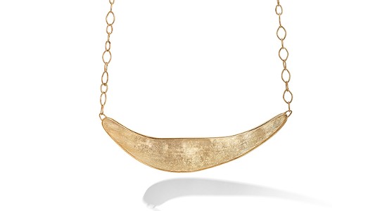 a yellow gold necklace with an organic shaped and textured piece of gold