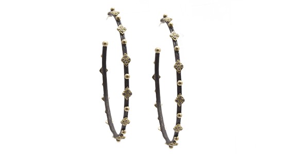 a pair of dark metal hoop earrings featuring yellow gold details