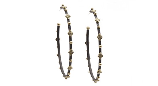 a pair of dark metal hoop earrings featuring yellow gold details