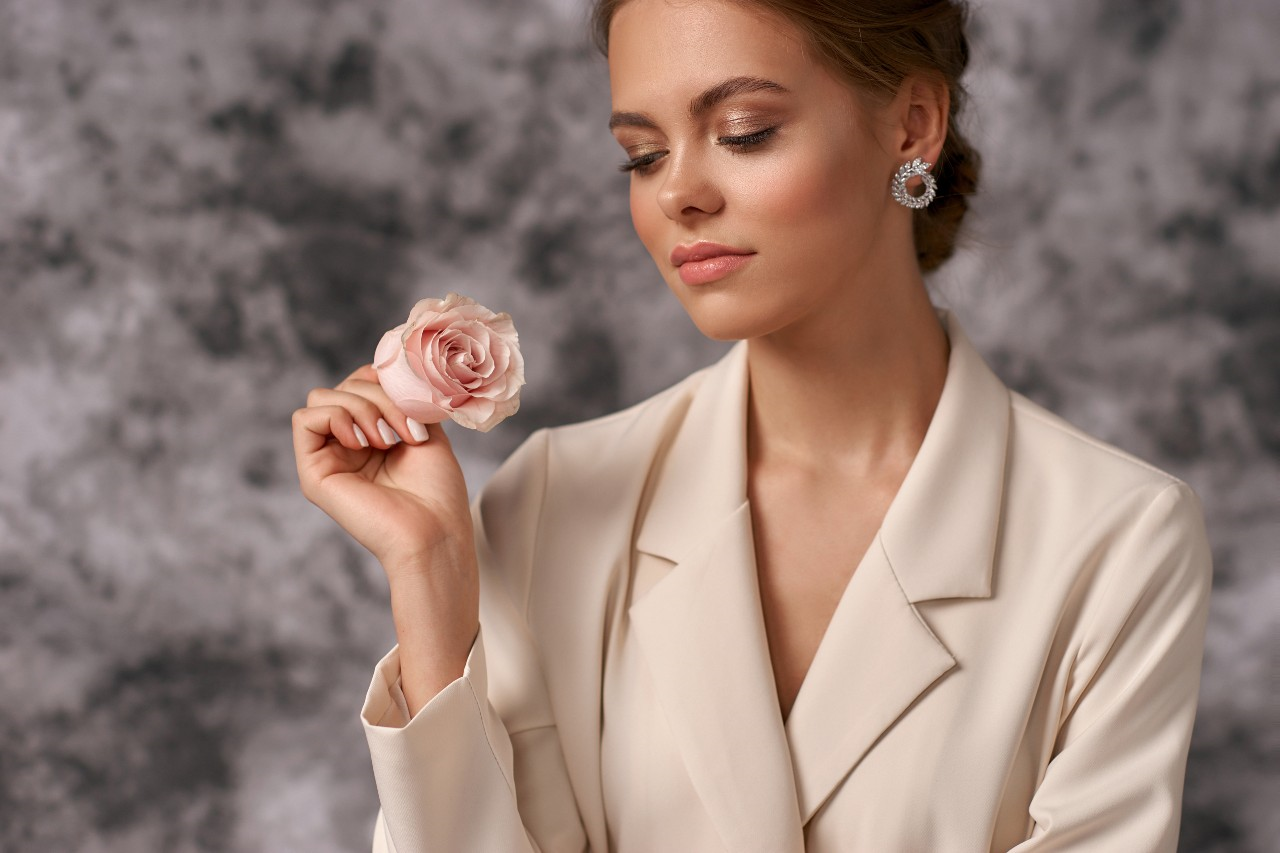 lady in professional attire, holding a rose, and wearing beautiful jewelry