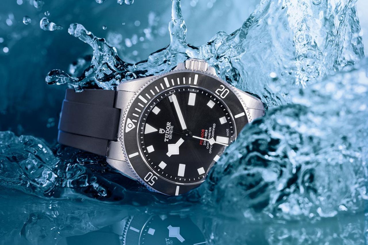 close up image of a TUDOR Pelagos watch with a black dial, bezel, and rubber watch strap splashing into the water