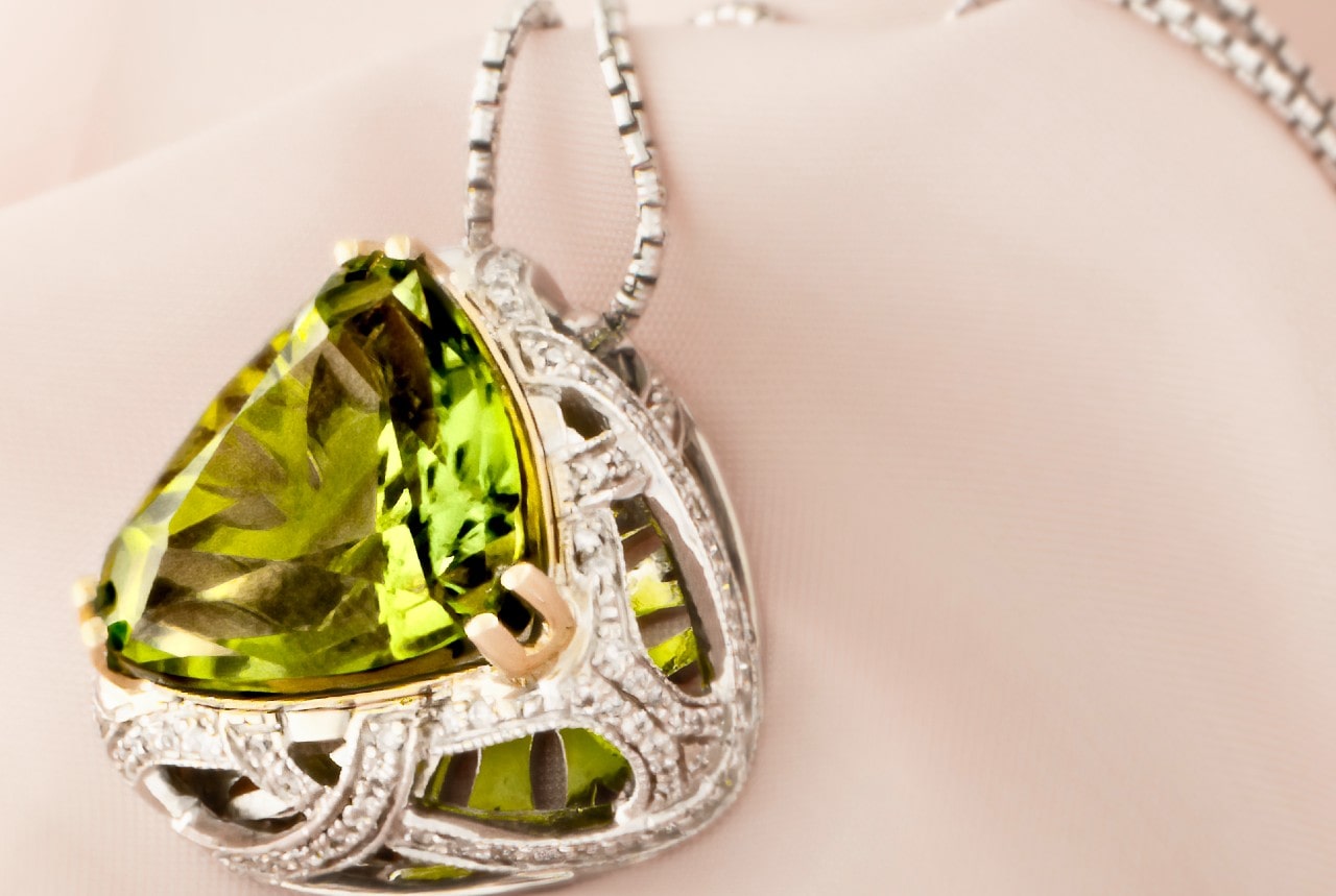 close up image of a white gold pendant necklace featuring a vibrant peridot