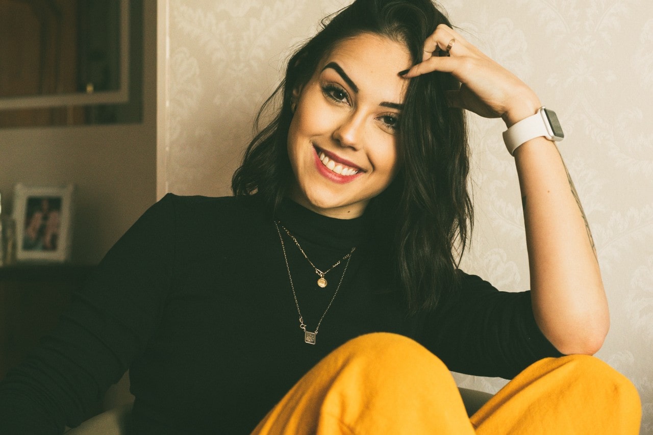 A woman in a black turtleneck wearing two layered necklaces.