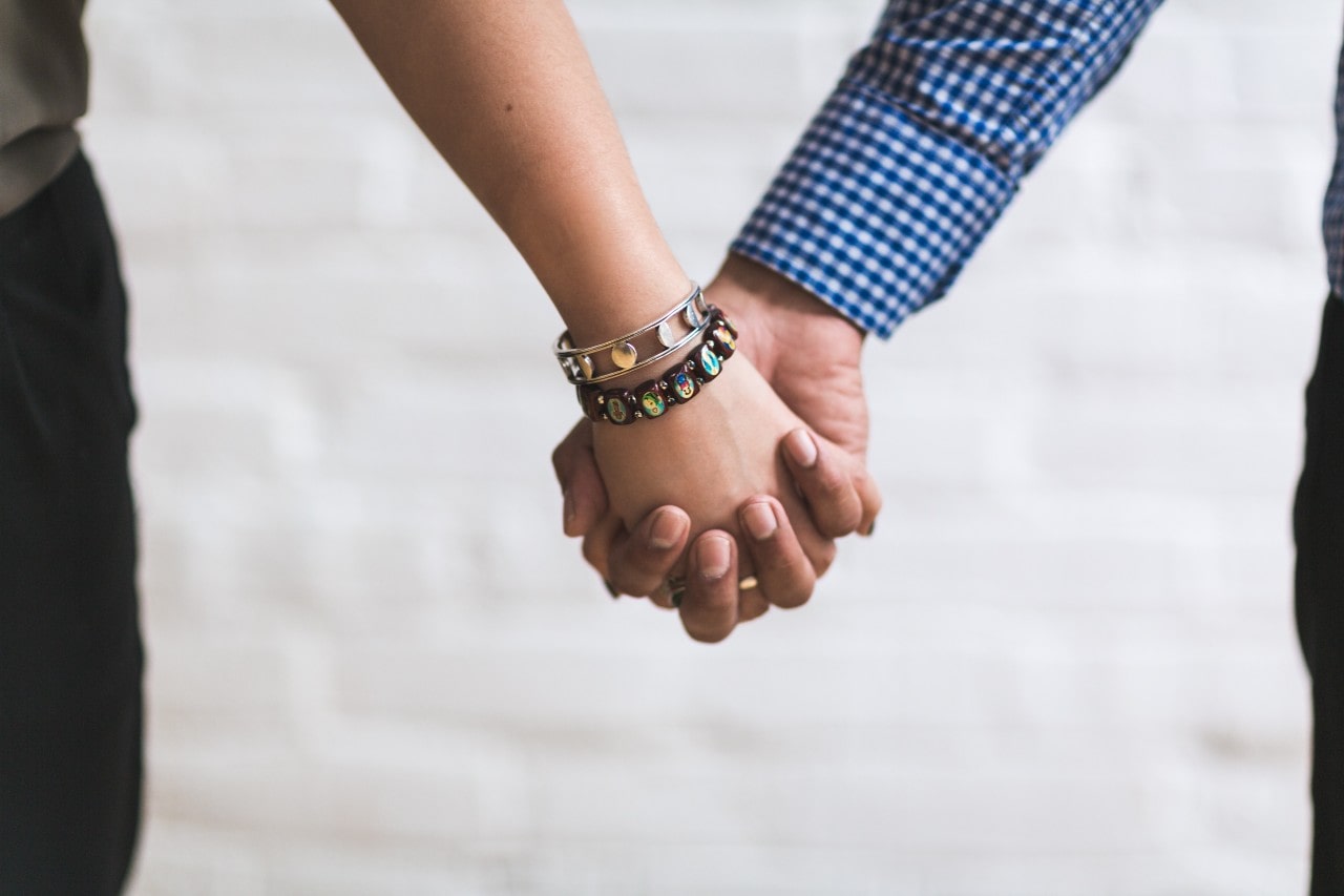 a couple holding hands, the woman wearing layered bangles.