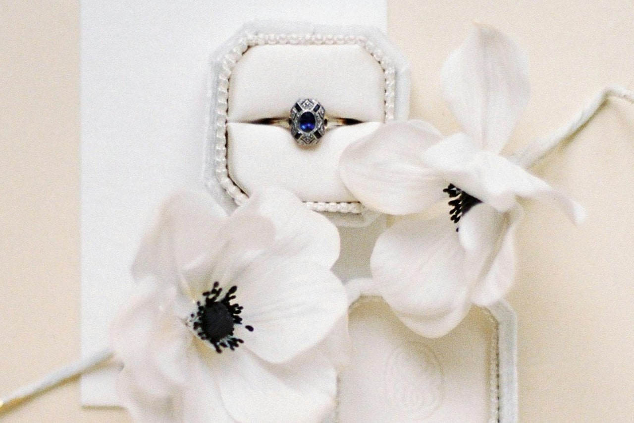 a unique vintage-inspired engagement ring with a blue center stone in a white box