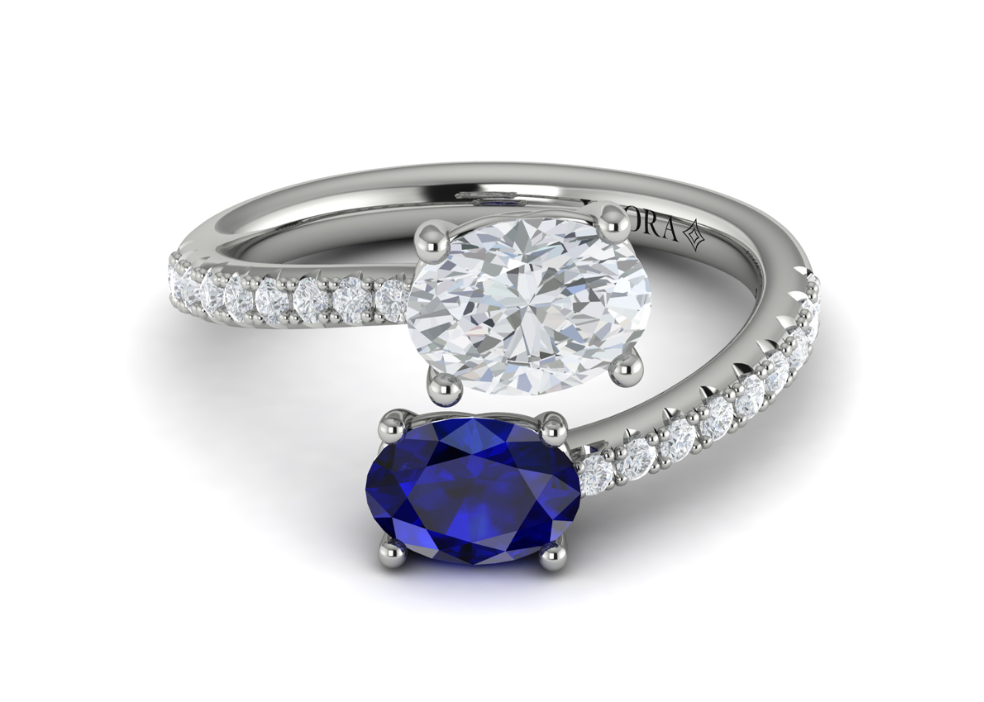 A white gold two stone engagement ring with oval cut diamond and sapphire on each end.