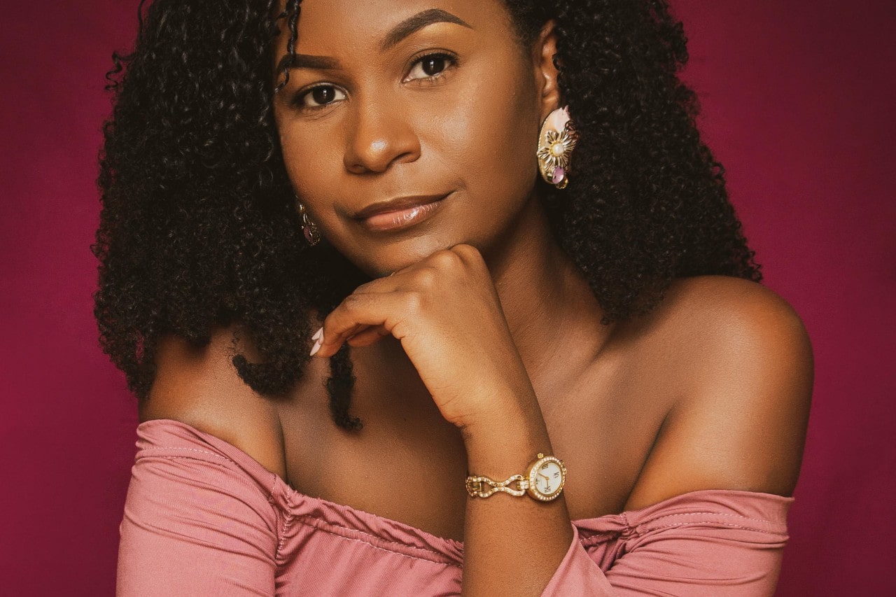 a woman wearing a pair of large earrings featuring pearls and a watch with a mother of pearl dial