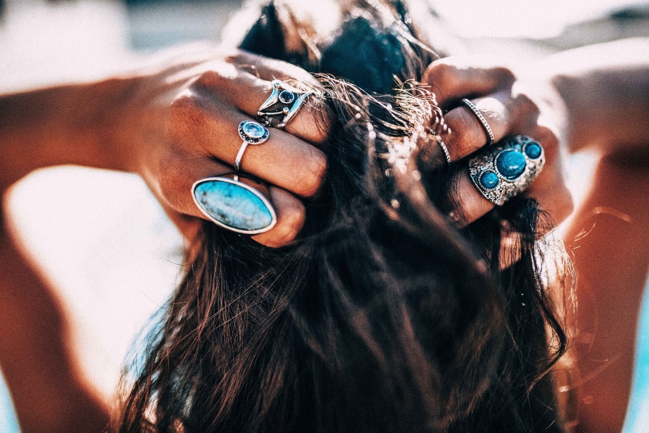 lady’s hands wearing rings combing her hair