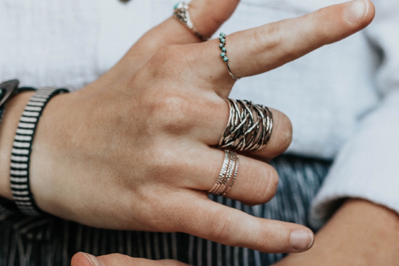 a hand wearing fashion rings with fingers extended