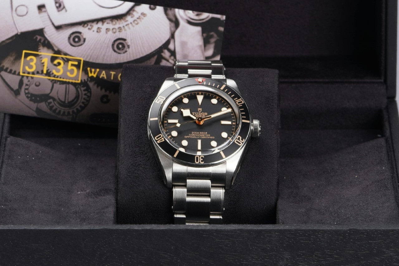 A view of a TUDOR watch displayed in-box in front of a card illustrating the watch’s movement.