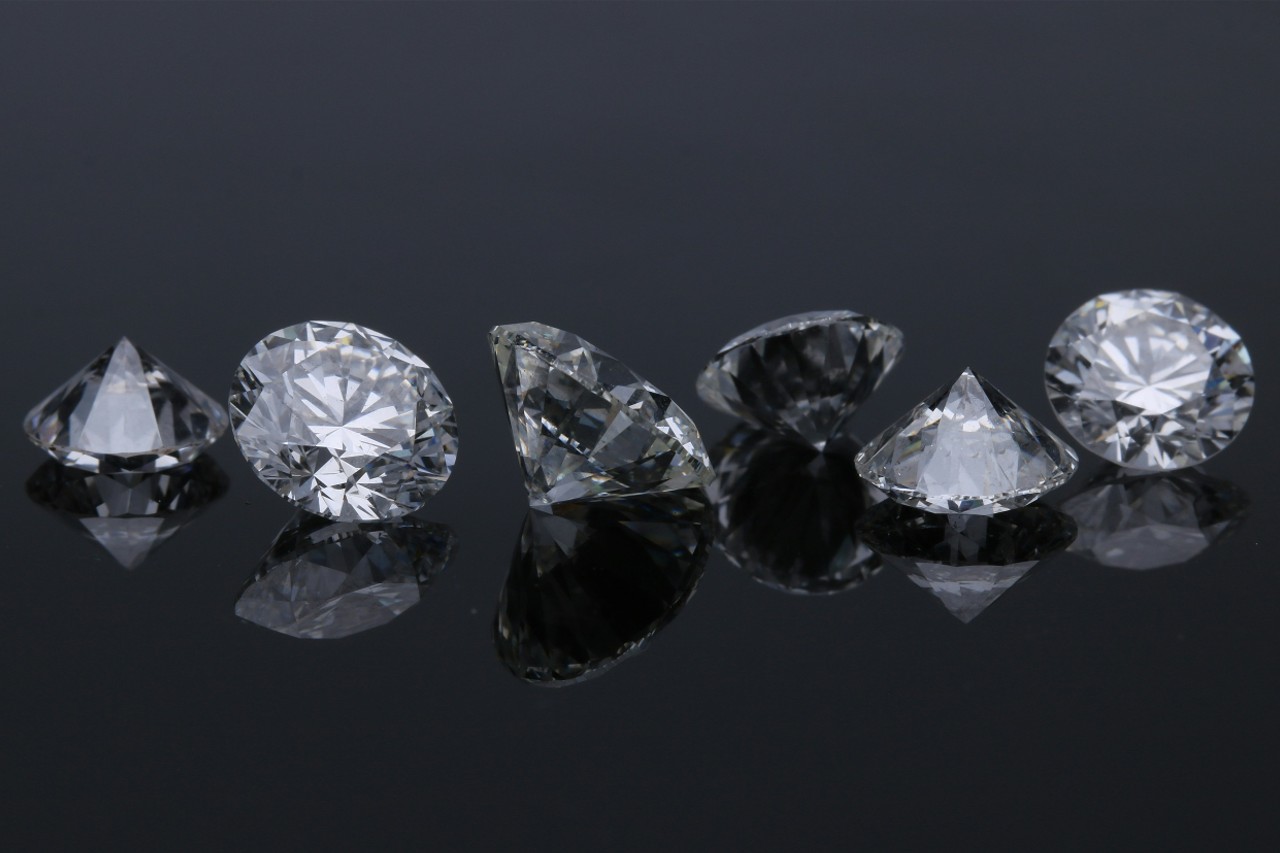 a line of six round cut diamonds on a dark, reflective surface