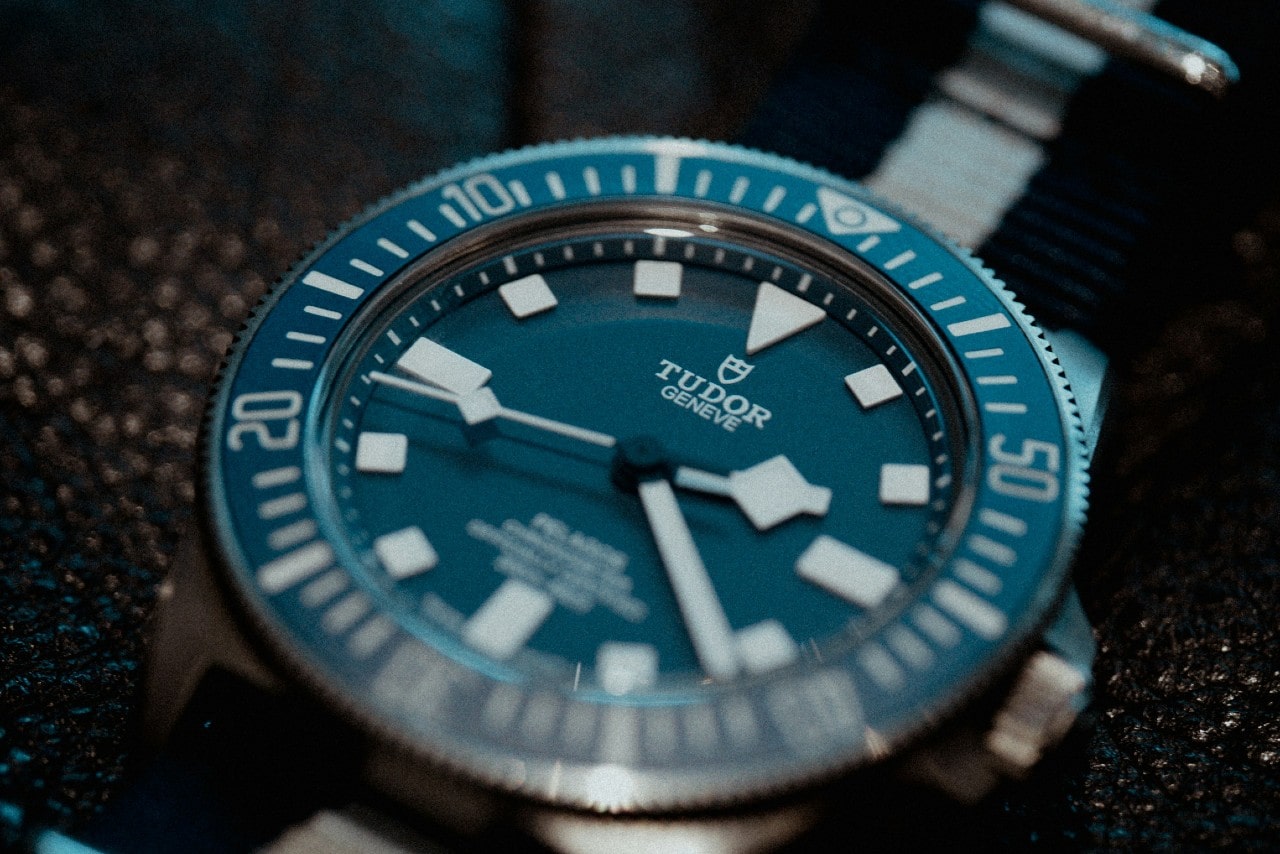 A close-up of a TUDOR Pelagos watch with a fabric strap, blue dial, and blue bezel.