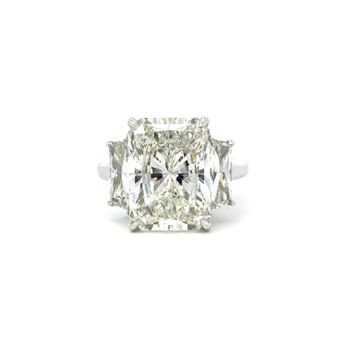 A radiant-cut diamond ring with a large central stone flanked by two smaller diamonds.