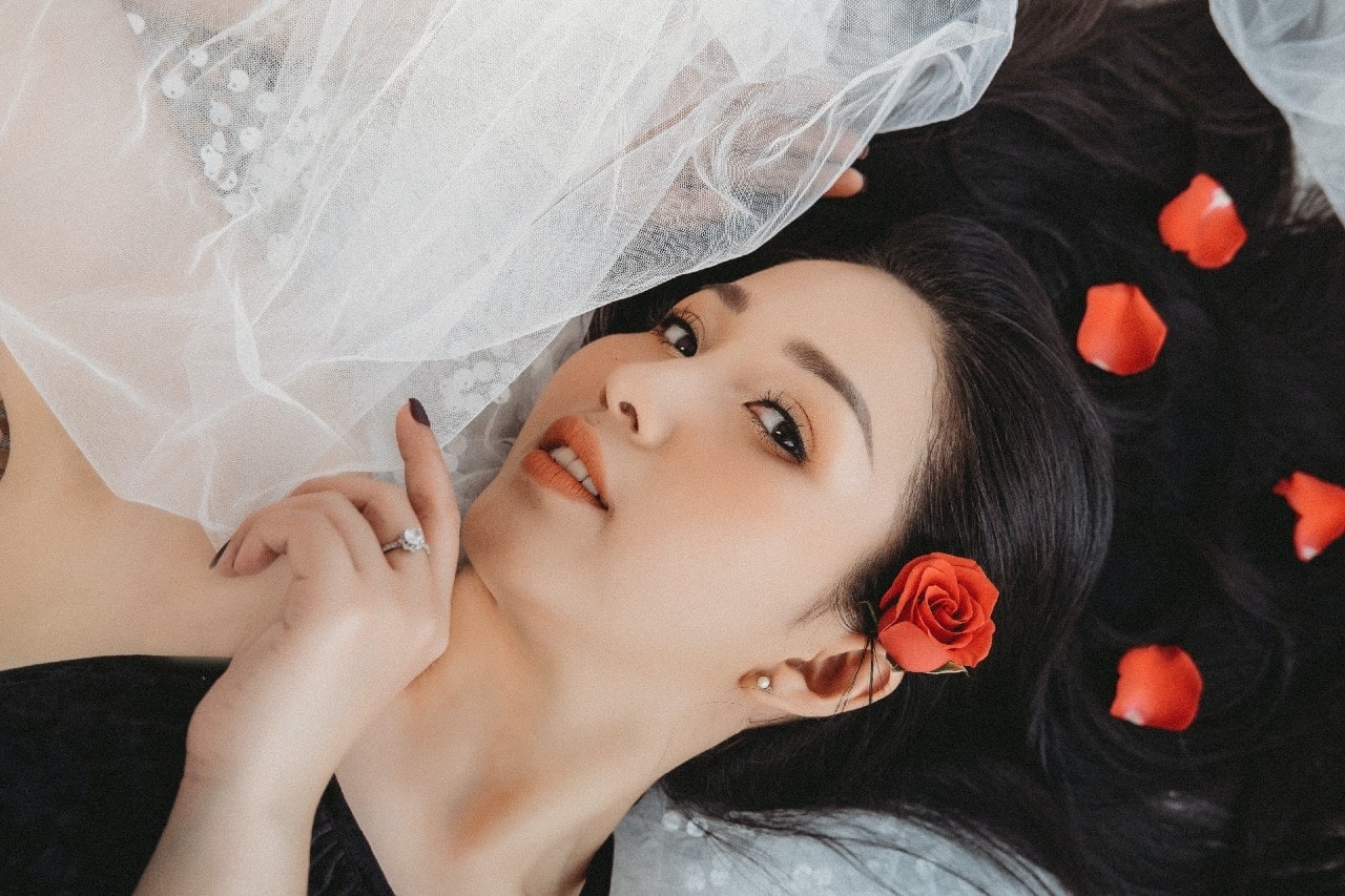 a bride lying down with flowers in her hair wearing a diamond engagement ring
