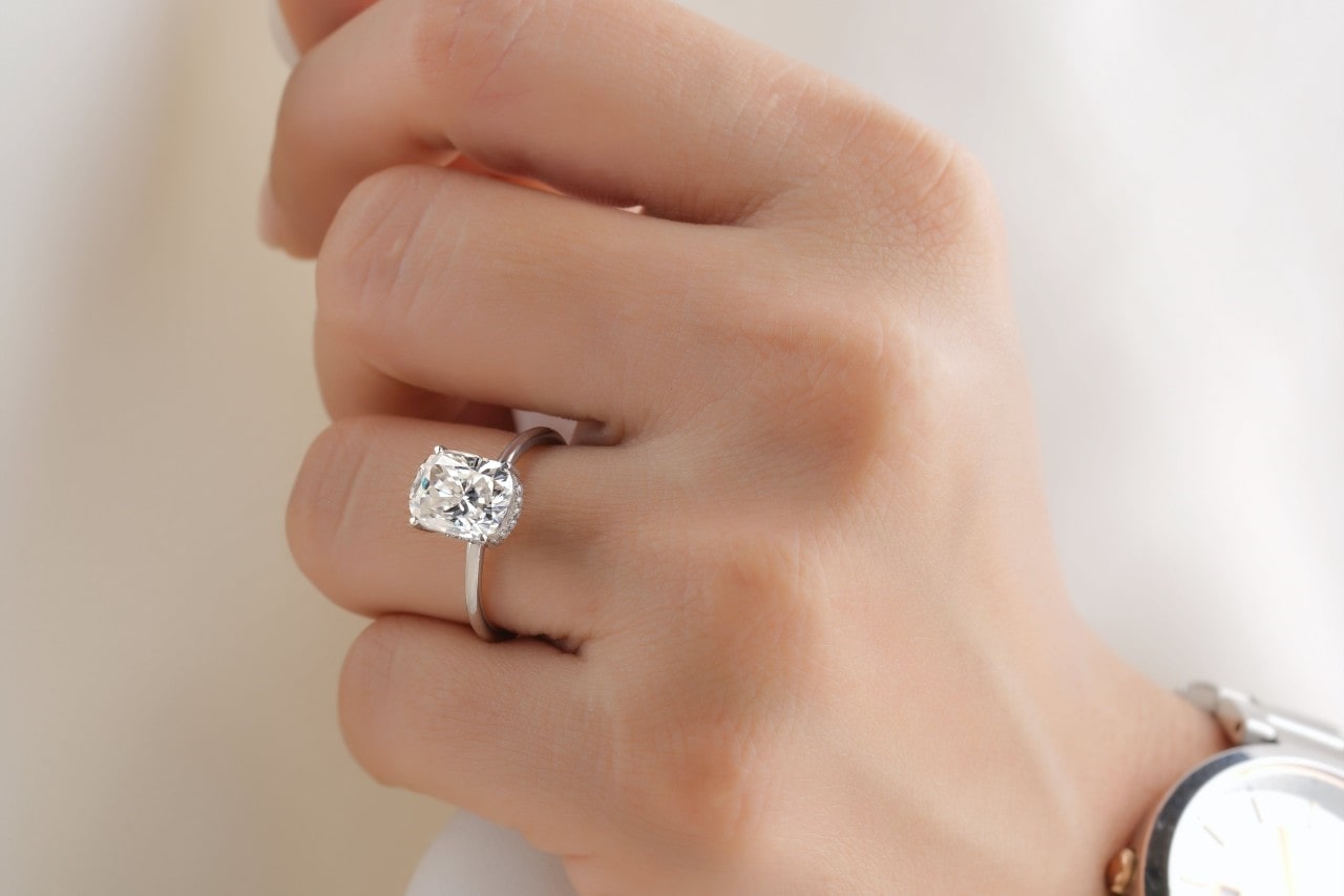 a close-up of a hand wearing a diamond engagement ring with a prong setting