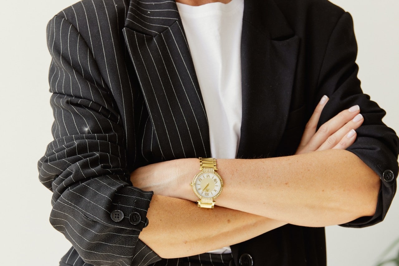 a lady’s torso and arms crossed wearing a dress watch