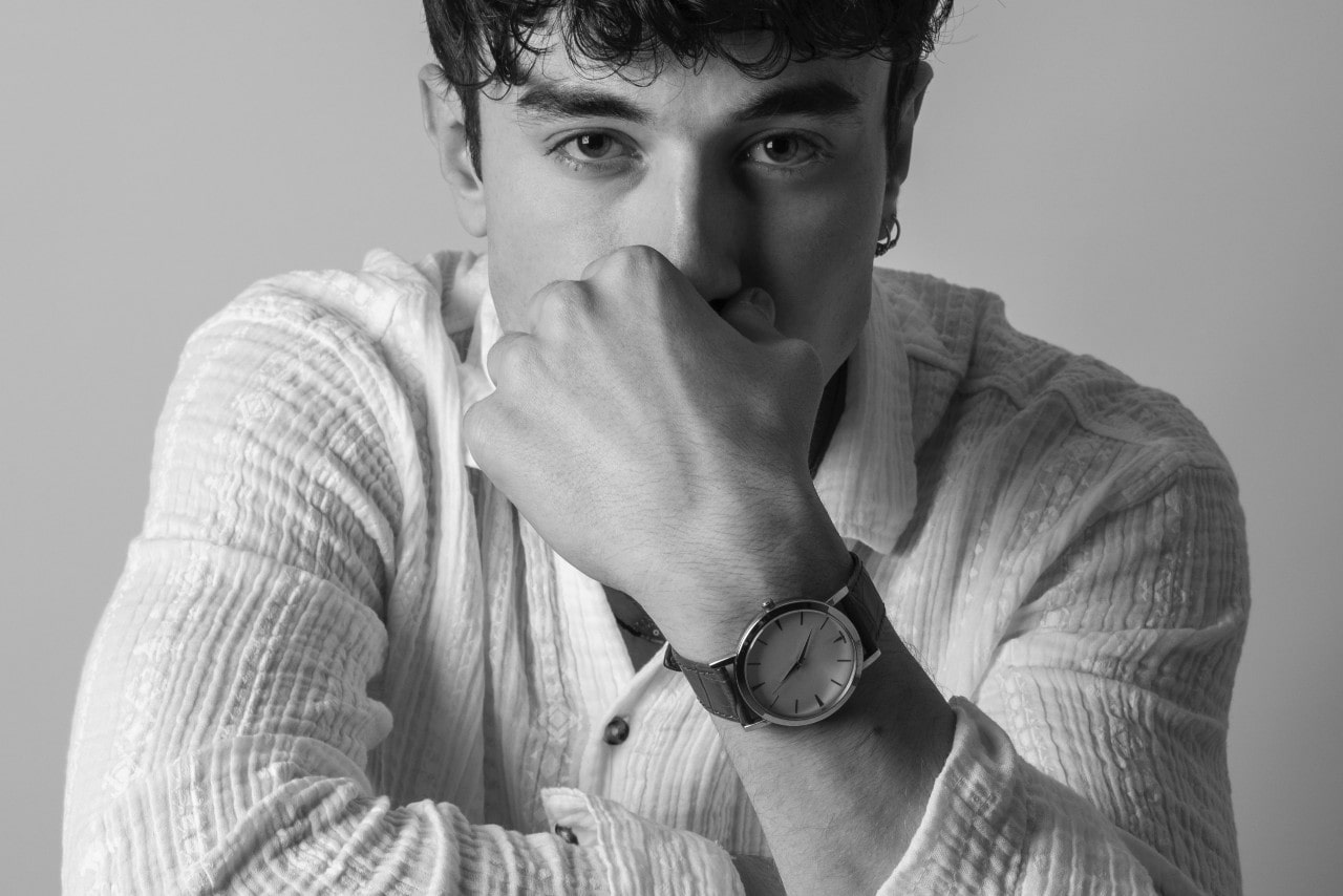 a man wearing a dress watch resting his face on his hand
