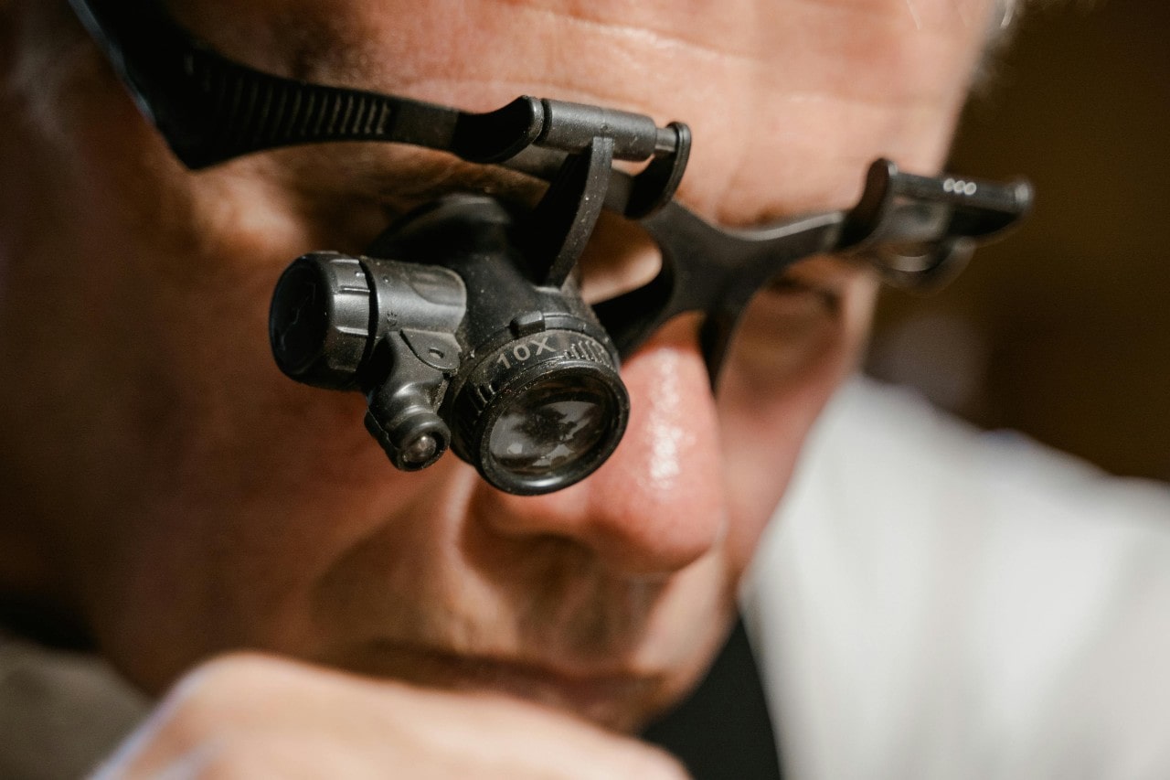 A close-up of a person wearing magnifying eyeglasses inspecting something closely