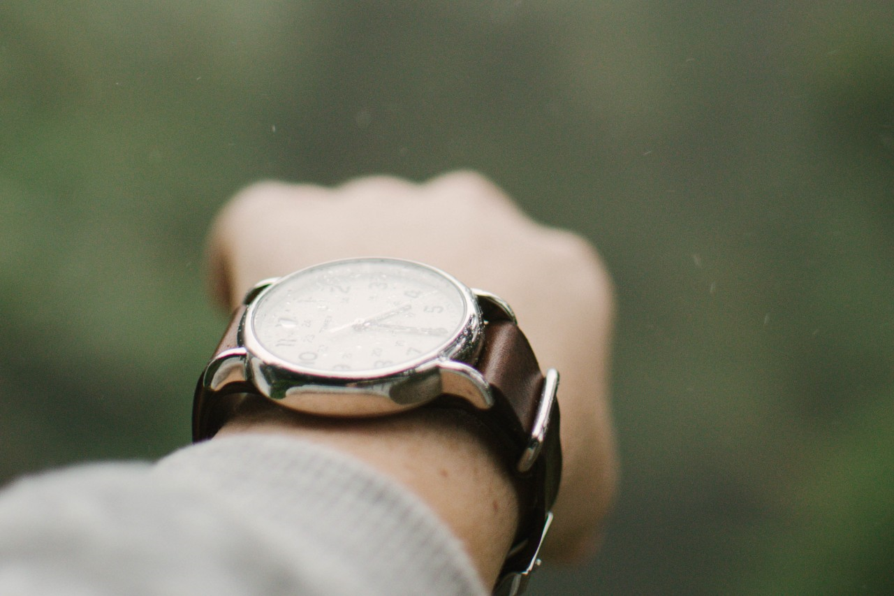a wrist wearing a luxury watch with a green background