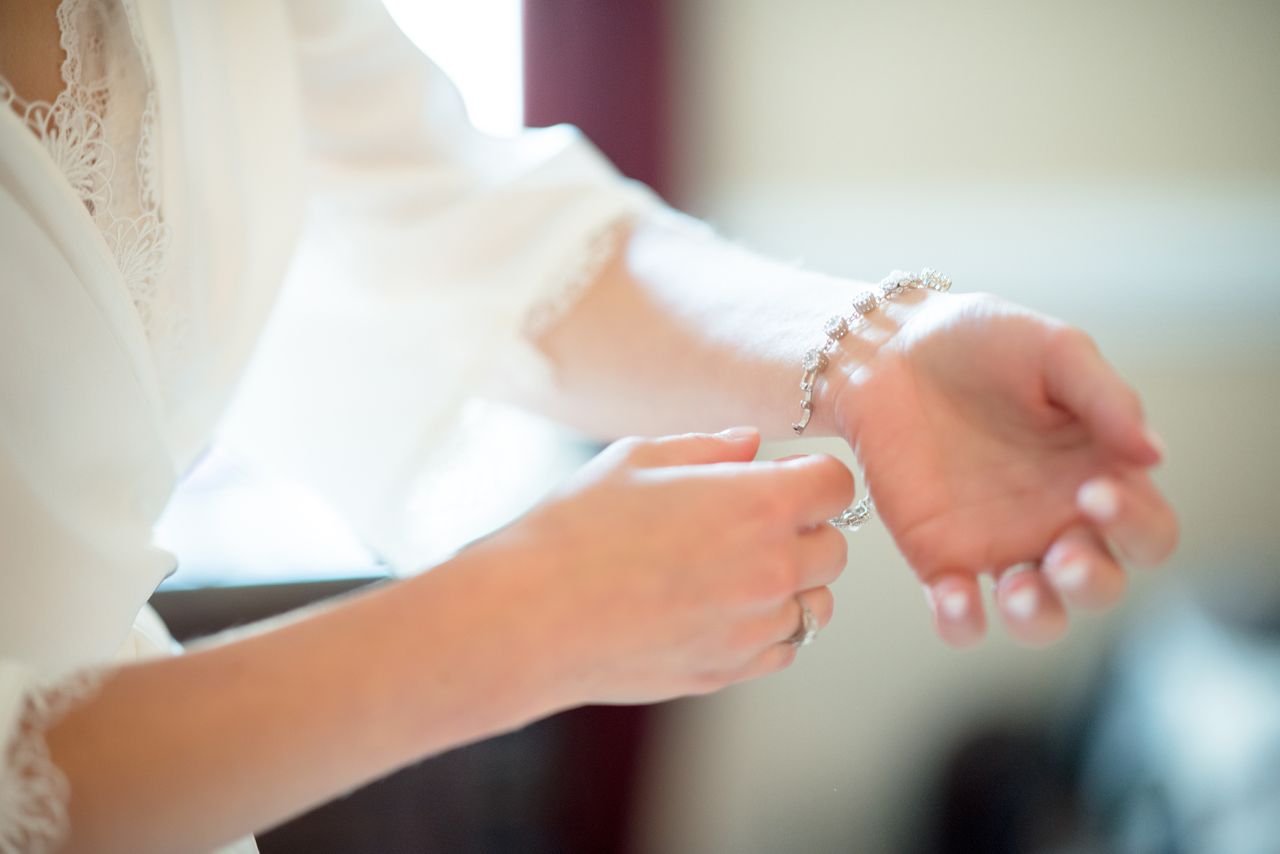 A woman putting on a diamond station gemstone bracelet A woman putting on a diamond station gemstone bracelet