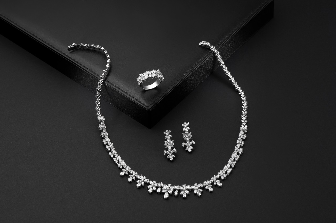 A diamond jewelry set, including a necklace, ring, and earrings, is arranged on a black background. A diamond jewelry set, including a necklace, ring, and earrings, is arranged on a black background.
