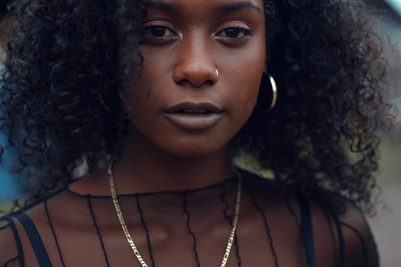 a woman wearing a black mesh top and a gold necklace.