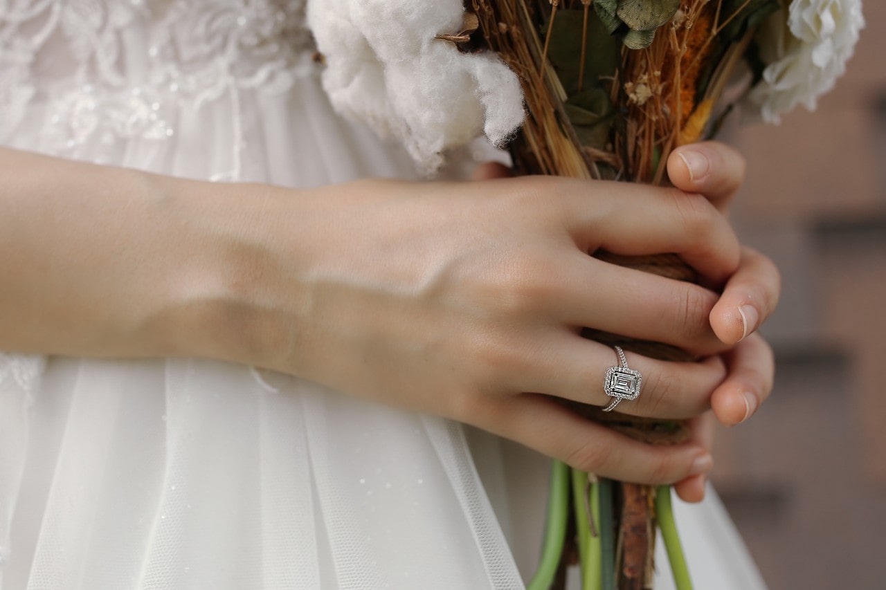 Bride holding her bouquet and wearing a silver, radiant cut engagement ring