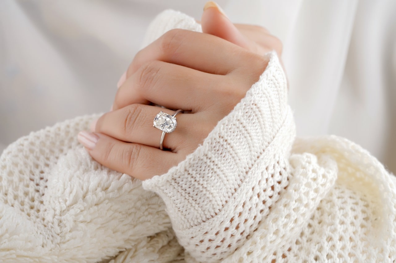Close-up image of a woman’s hand wearing a radiant cut diamond ring with a thin silver band