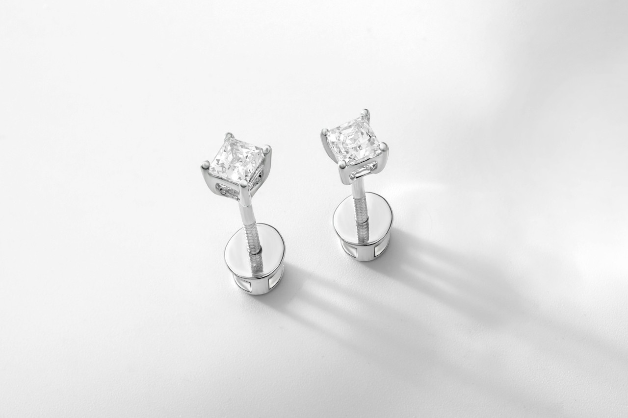 a pair of princess cut diamond stud earrings on a white surface a pair of princess cut diamond stud earrings on a white surface